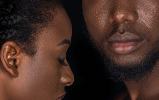 beautiful young african american couple with water drops on faces posing isolated on black